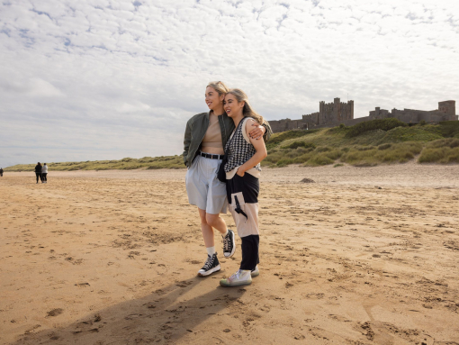 Two women hugging on the beach near a castle