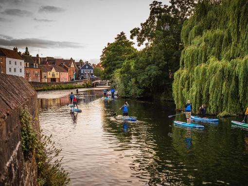 A group of people paddleboarding on the River Wensum