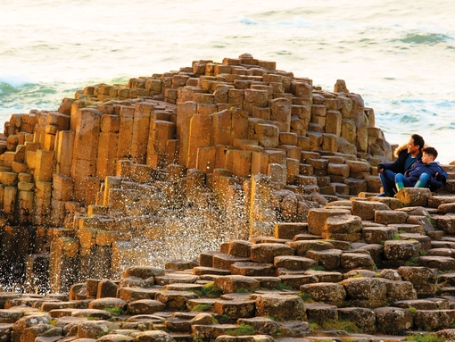 Man and boy sitting on the red basalt columns
