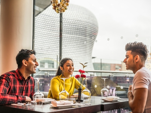 Three young people sat at a dining table with high views