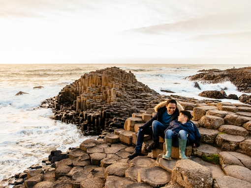 Man and boy sitting on the red basalt columns