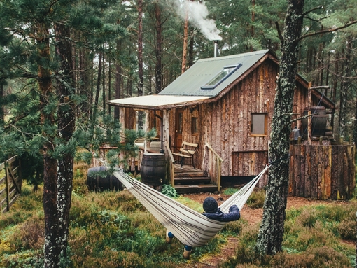 Person relaxing in hammock outside wood cabin