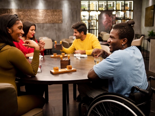 Group of friends, one wheelchair user, sat around a table