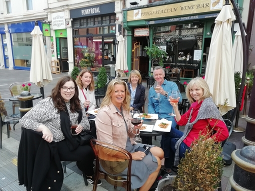 A group of people eating and drinking at an outside table at Cosmo, Cardiff