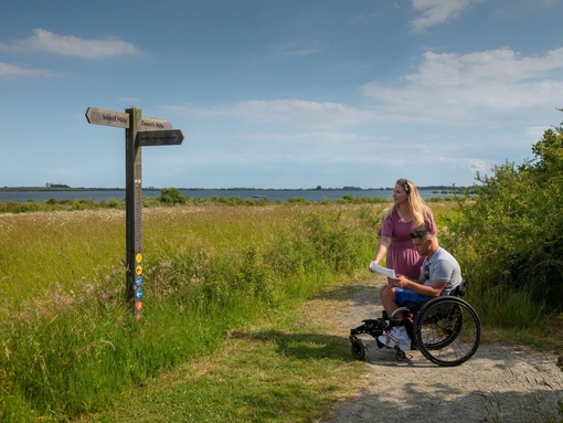A man who uses a wheelchair and a woman review a map in the countryside