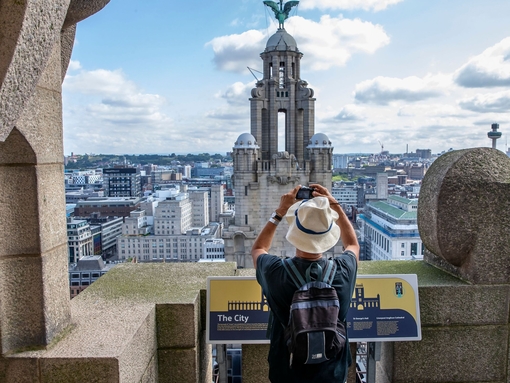 Gentleman photographing the tower in the skyline from the roof of the Royal Liver Building 360, Merseyside.