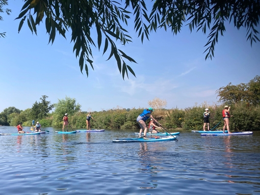 A group of people paddleboarding down the river Avon near Stratford-upon-Avon