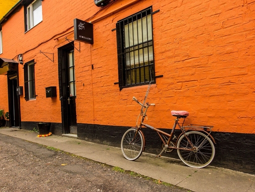 Bicycle parked outside jewellery boutique with orange painted wall in the Hidden Lane, Glasgow.