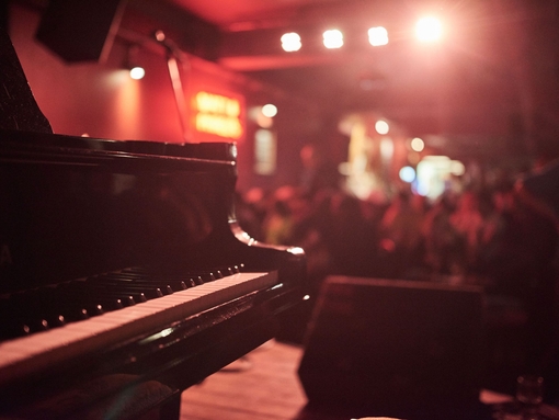 Pianist playing in a moodily lit bar. Red lighting
