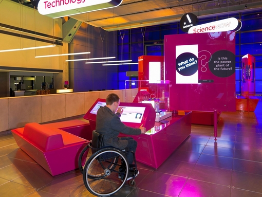 Male wheelchair user using interactive display at museum