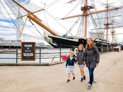 A family walking alongside a ship at a dock