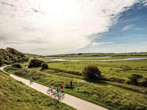 A family cycling along path through the wide open landscape