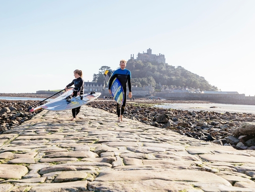 Windsurfer walking across the exposed causeway path of stone