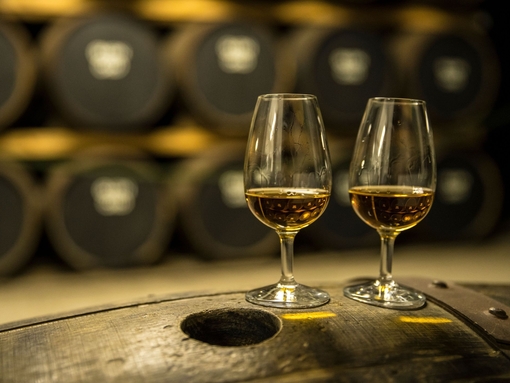 Two glasses of whisky standing on an oak barrel