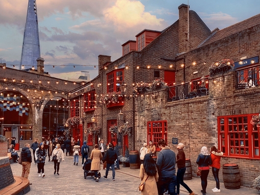 People walking past a pub, in Southwark with the Shard building in the distance