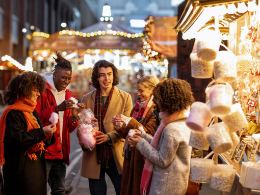 Eine Gruppe junger Freunde teilt sich auf dem Weihnachtsmarkt eine Tüte mit Zuckerwatte