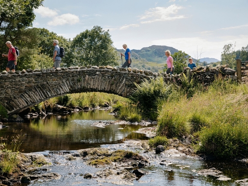 Group of friends out walking in the lakes crossing bridge in the Lake District