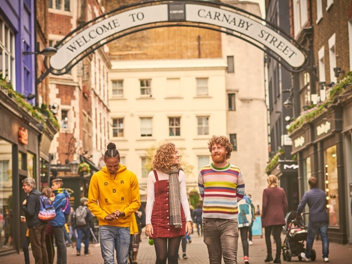 Una mujer joven y dos hombres jóvenes caminan por una calle