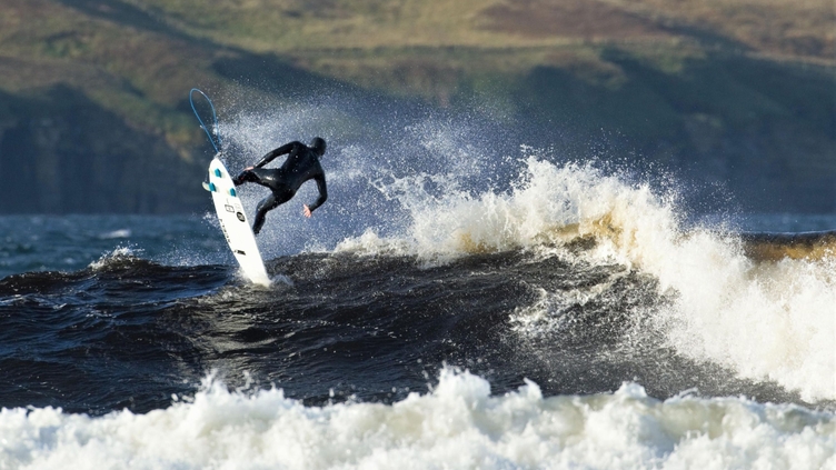 A surfer riding waves off the coast of the UK