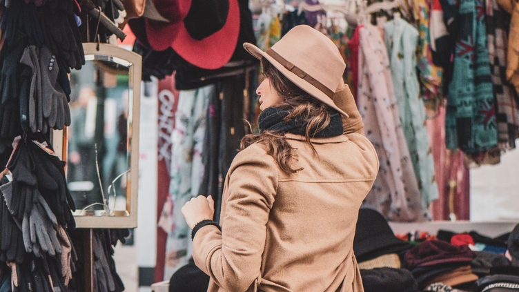 A woman trying on hats at a stall in Portobello Road Market, London