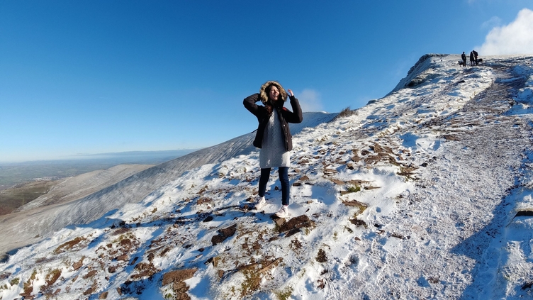 Woman standing in a snowy landscape on the side of a hill