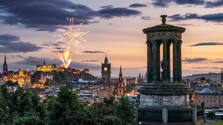 Fireworks at dusk in the sky over historic monument.