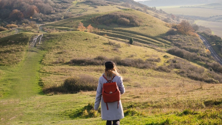 Woman walking a path high up on a ridgeway in the sunshine