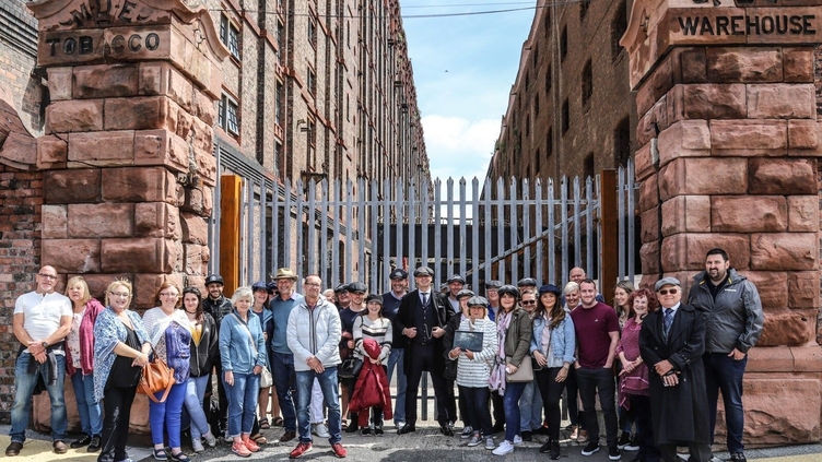 A Peaky Blinders tour group posing outside an industrial warehouse in Liverpool