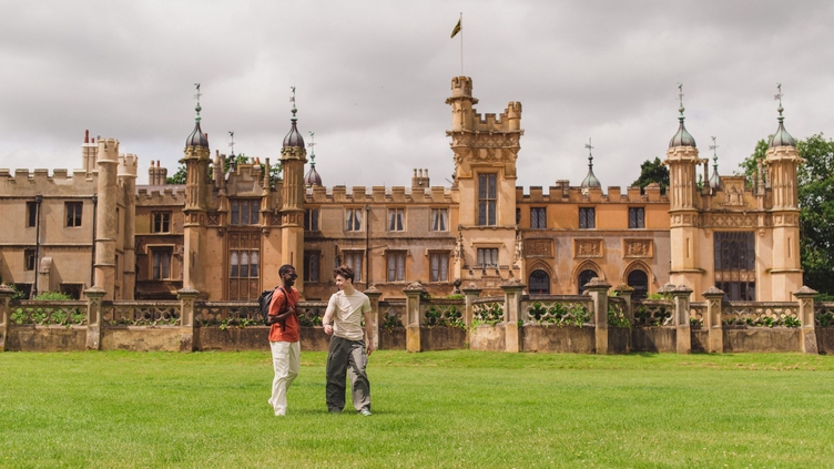 Two young men walk in the grounds of a heritage house
