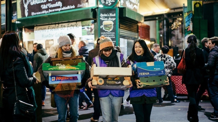 Tres mujeres cargando pequeñas cajas de fruta y verdura en Borough Market