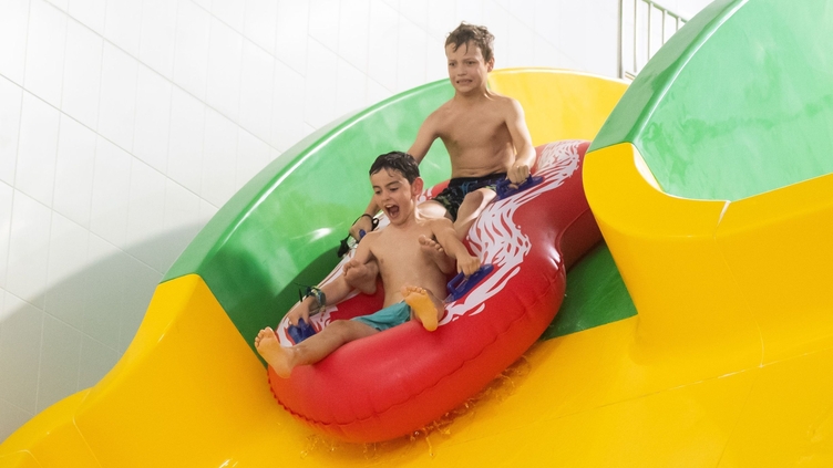 Dos niños se deslizan por una piscina hinchable en The Wave, en Coventry.