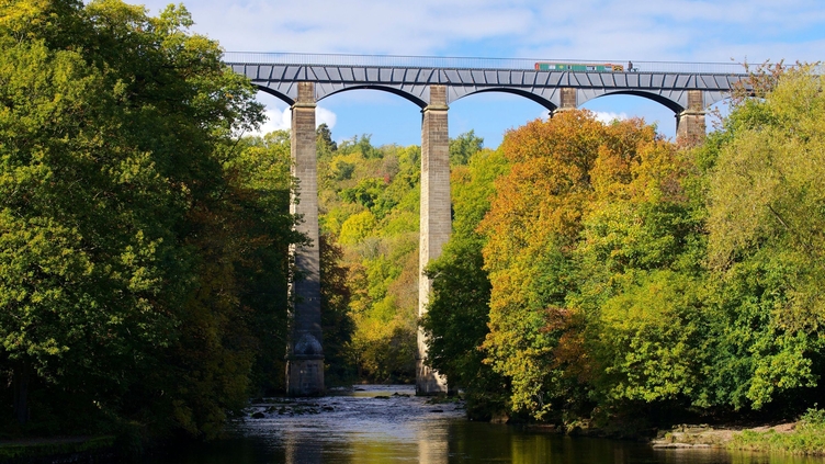 A tall aqueduct spanning a pretty stream.