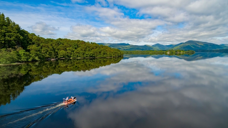 Un hombre impulsa una lancha motora en las aguas de Loch Lomond, Escocia