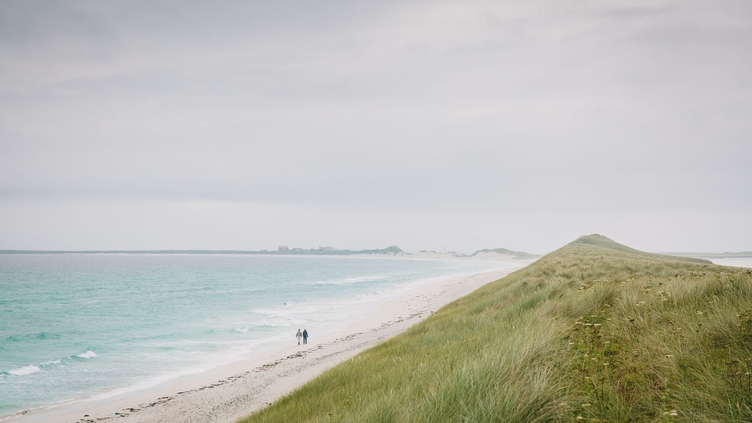 Two people walking along large empty beach, Tresness Sanday, Orkney