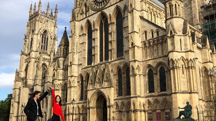 Man twirling a woman outside a historic building