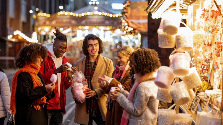 Group of young friends sharing a bag of cotton candy at the Christmas market