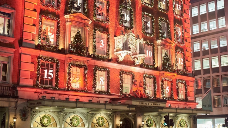 Multitud de personas de noche en la calle frente a Fortnum & Mason, Londres
