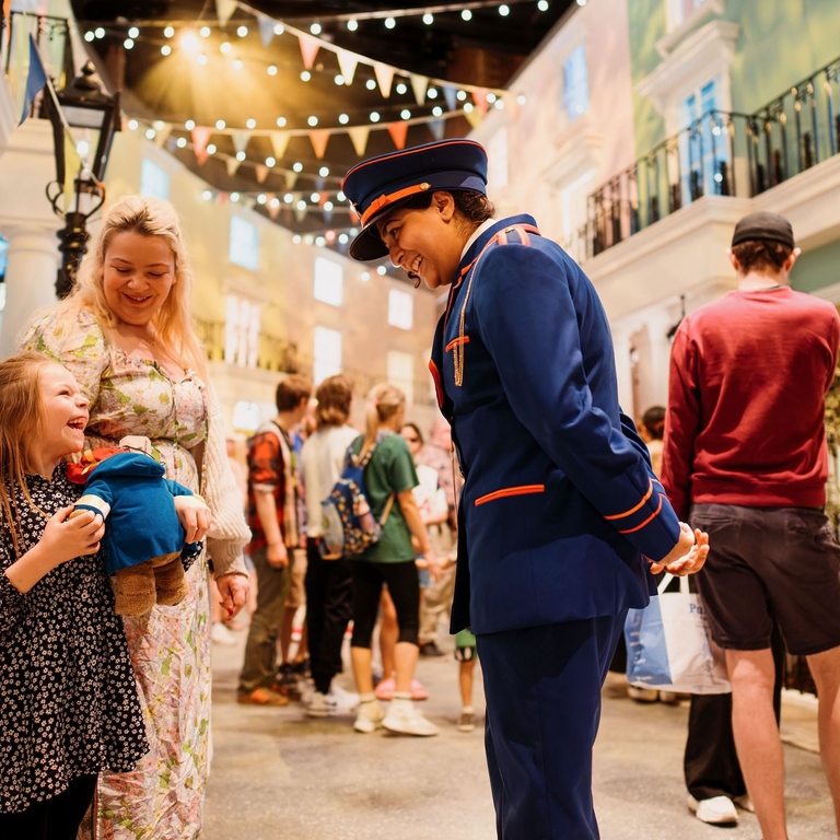 Character actors talking to a young child on the set of a stage.