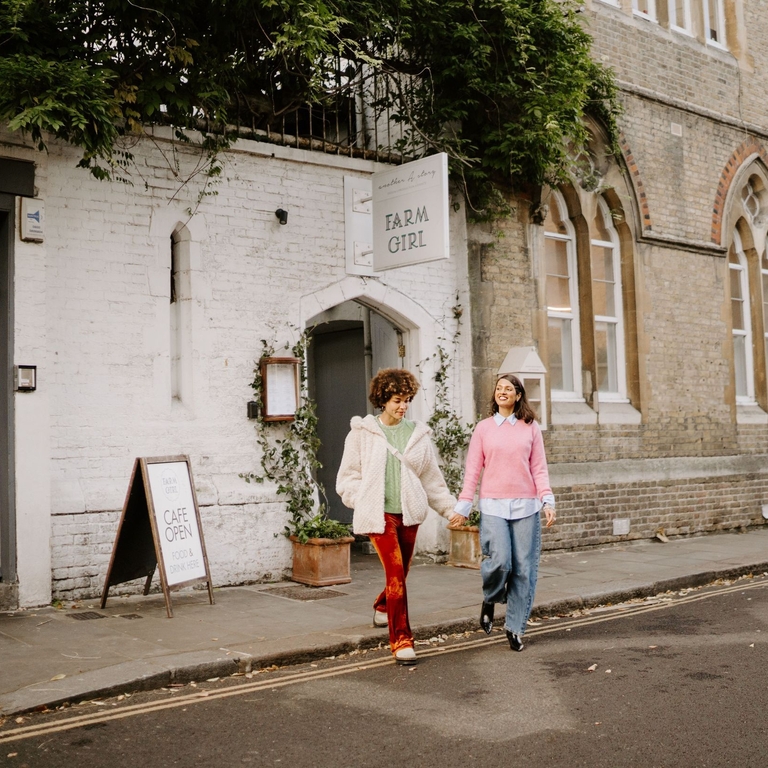 Two women leaving a cafe holding hands.