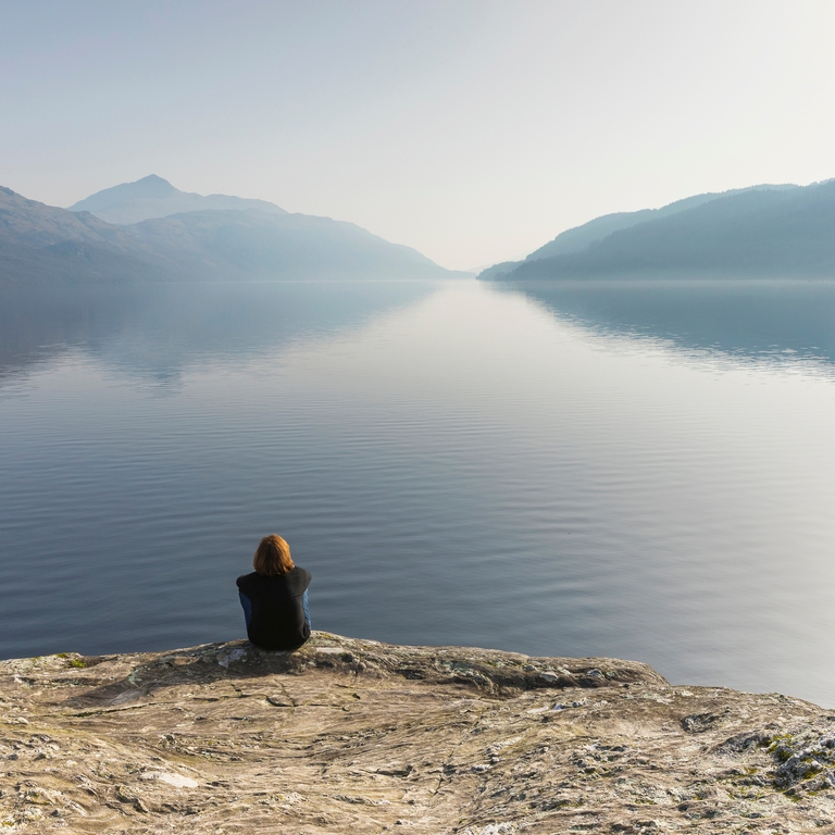A woman sitting and looking out across Loch Lomond
